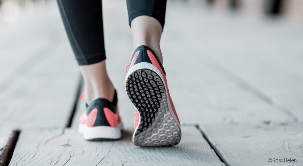 Foto: Zwei Füße von hinten, die Laufschuhe tragen; der rechte Fuß geht auf Zehenspitzen sodass die Schuhsohle aus Polyurethan sichtbar wird.