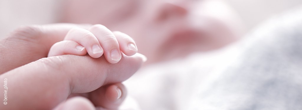 Foto: Die Hand eines Babys greift nach dem Finger der Mutter.