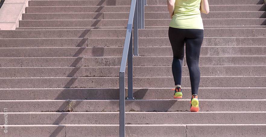 Foto: Eine Person in Sportsachen joggt eine lange Treppe hoch.