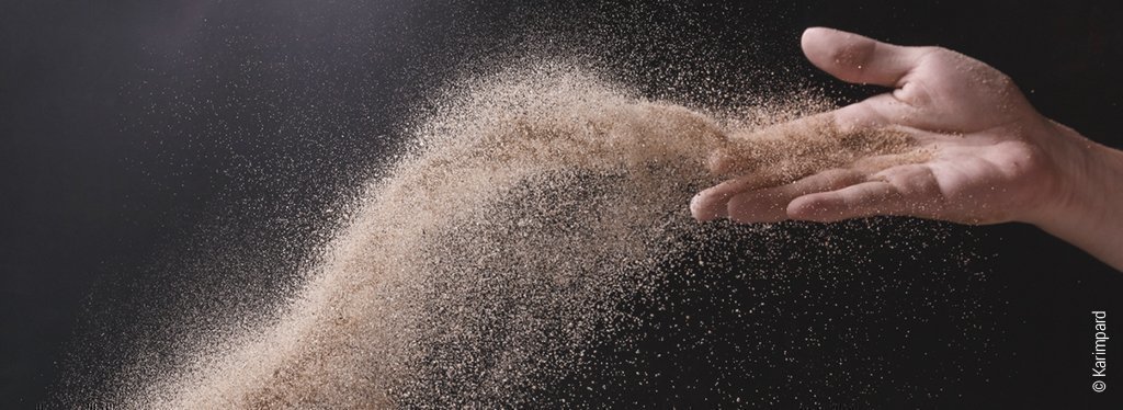 Symbolfoto Sandmann streut Schlafsand: Eine Hand streut mit Schwung etwas feinen Sand.