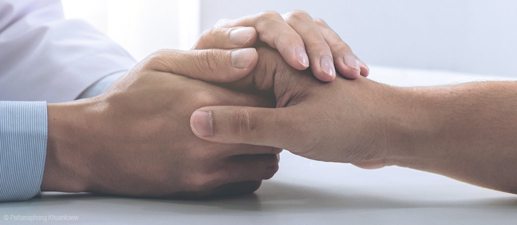 Foto: Ein Arzt hält die Hand eines Patienten. 