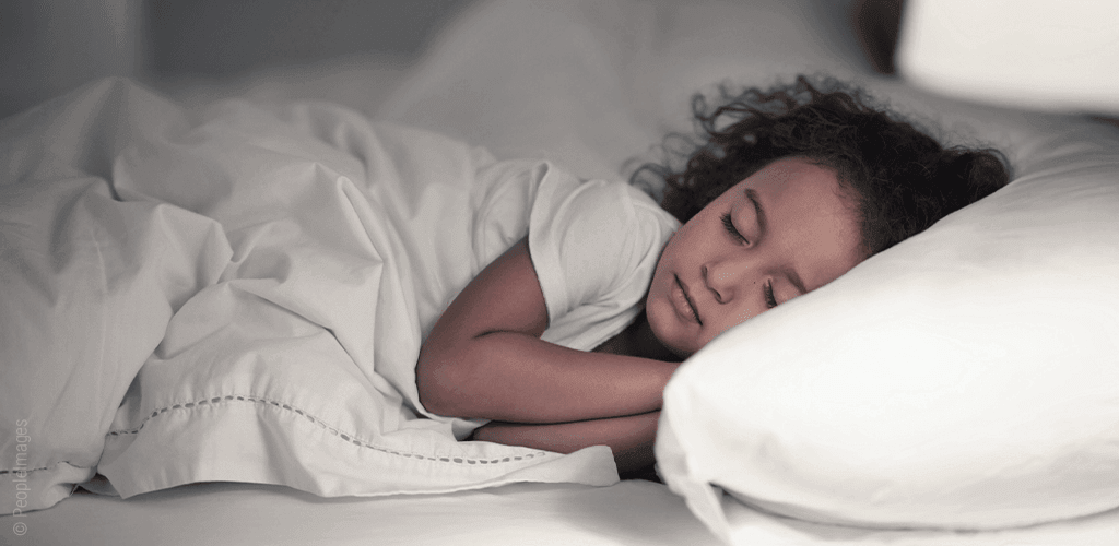 Foto: Ein Mädchen liegt im Bett und schläft.