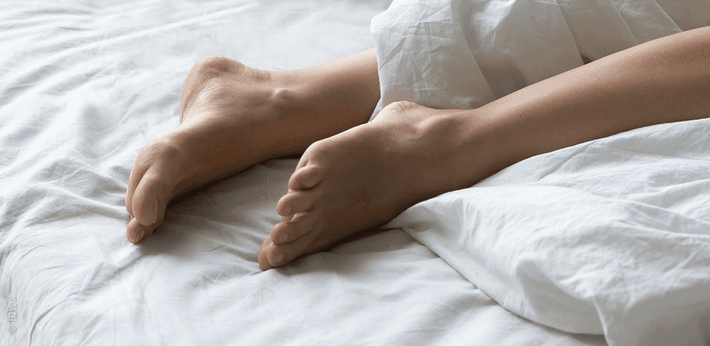 Foto: Ausgestreckte Füße auf einer weißen Matratze.