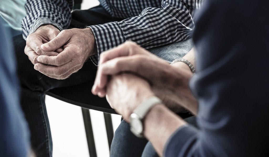 Foto: Die Hände zweier Personen, die sich gegenüber sitzen im Fokus.