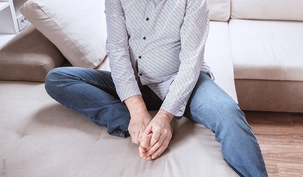 Foto: Eine Person sitzt im Bett und massiert sich die Fußsohlen.