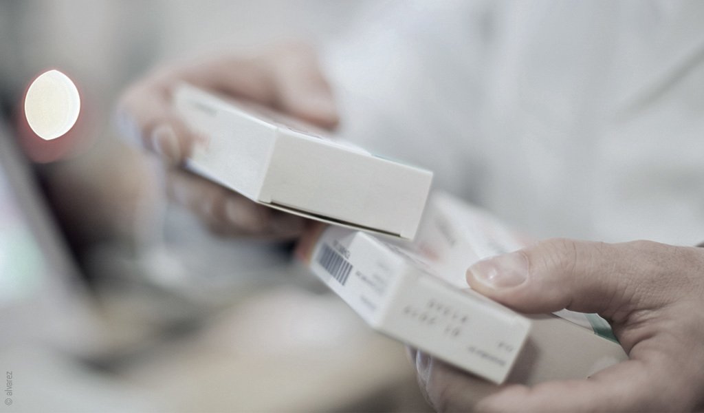 Foto: Fokus auf die Hände einer Person, die verschiedene Packungen Medikamente hält.