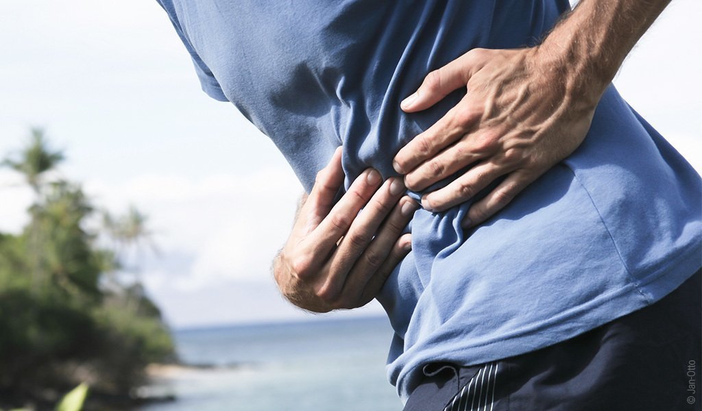 Foto: Eine Person betreibt Sport und hält sich dabei den Bauch