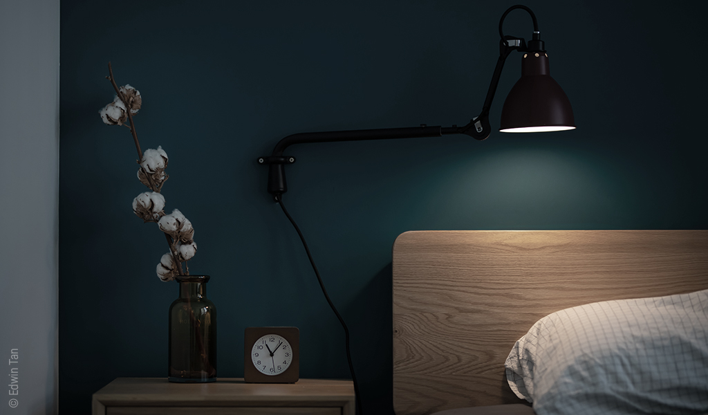 Foto: Eine Stehlampe beleuchtet den Kopfteil eines Betts.