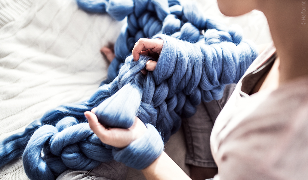 Foto: Eine Person strickt eine Chunky-Decke mit der Arm-Knitting-Technik.