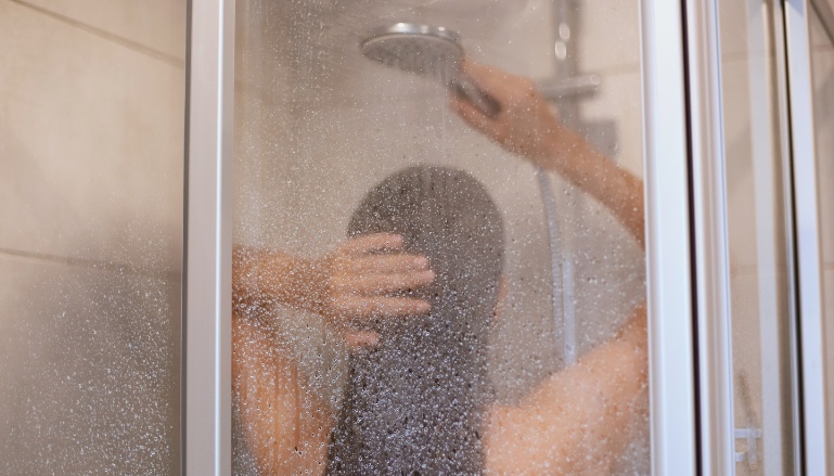 Pessoa no chuveiro tomando banho de água fria