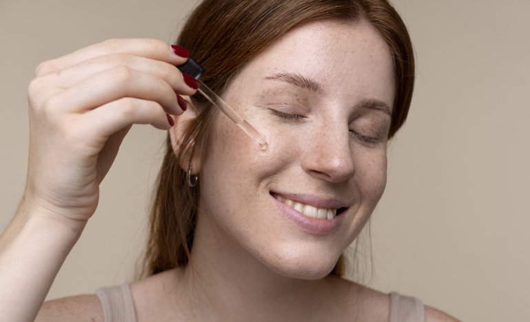 Mulher sorridente usando conta gosta para aplicar vitamina e no rosto