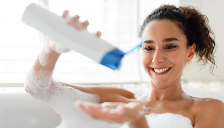 Mulher na banheira colocando sabonete líquido 