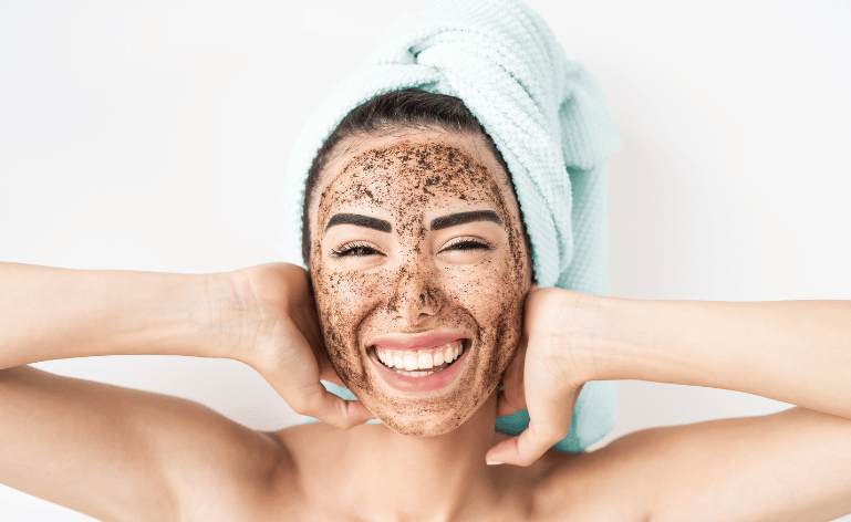 Mulher sorrindo com esfoliante no rosto.