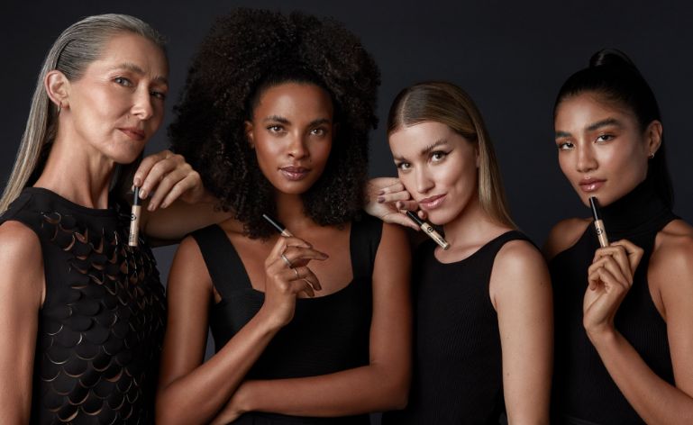Quatro mulheres de etnias diferentes, todas vestidas de preto e encarando de frente para a imagem. Elas sabem como escolher corretivo.