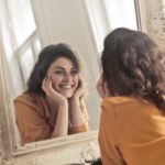 Mulher sorrindo ao se olhar no espelho