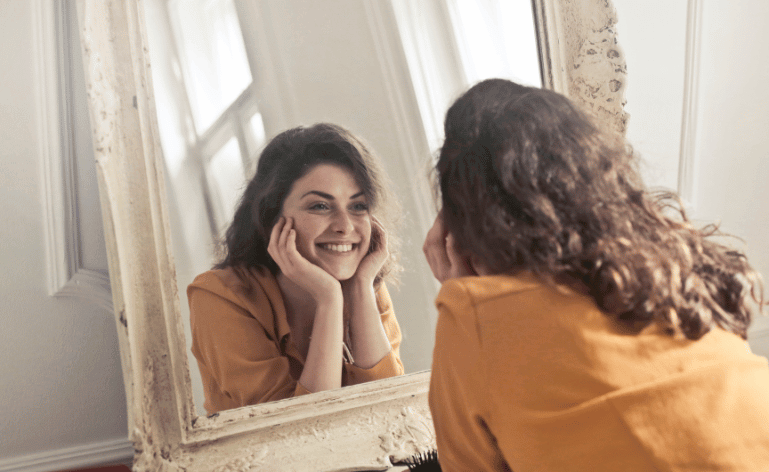 Mulher sorrindo ao se olhar no espelho