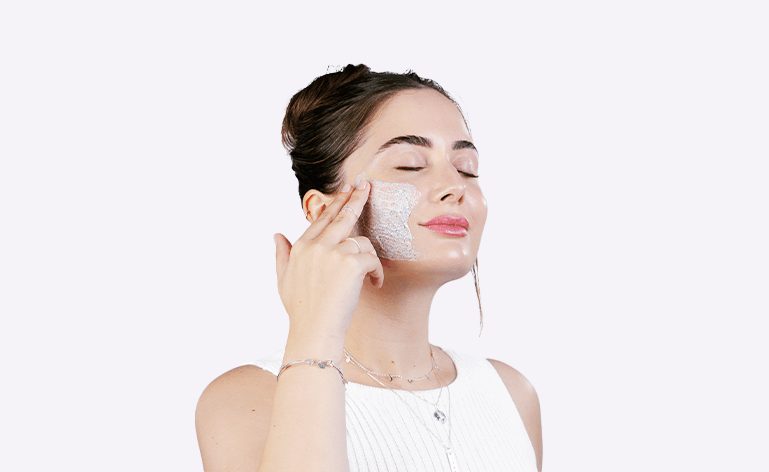 Mulher branca tocando o rosto após aplicar produto para renovação celular.