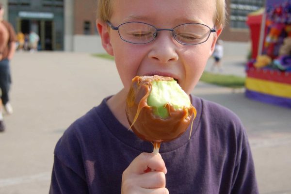 A young Fairgoer enjoys a caramel apple in front of the Grandstand.