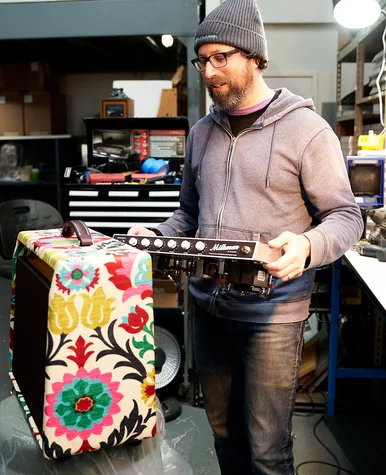 Tim Marcus holding a Milkman Sound chassis next to a floral-fabric-wrapped cabinet