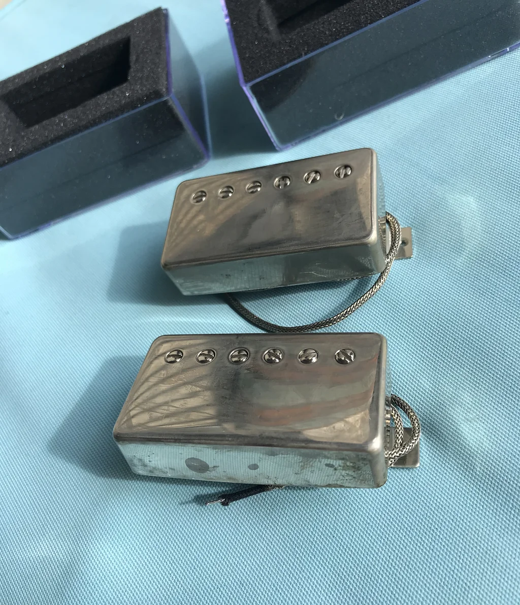 Flynn A5 Bucker Set — two covered humbuckers with aged nickel covers resting outside their foam boxes