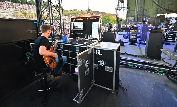 Justin dialing in a guitar side of stage at an outdoor venue