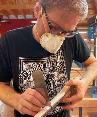 Cody Gleason spraying finish on a neck