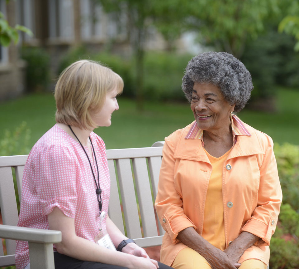 resident chatting with an associate outside on a bench
