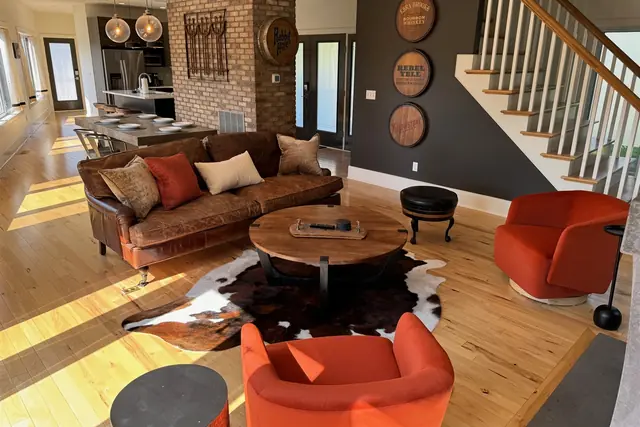 The Reserve: 5BR Louisville Retreat with Hot Tub & Game Room: Living room with leather sofa and staircase