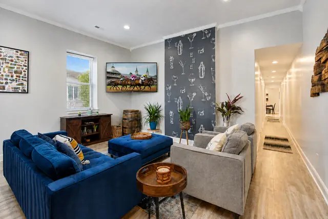 The Julep House NuLu: Living room with navy sofa and cocktail wallpaper