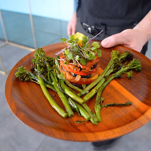Pan - seared salmon on a wooden plate served with charred broccolini