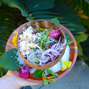 Hand holding a cucumber and coconut salad served in a halved coconut