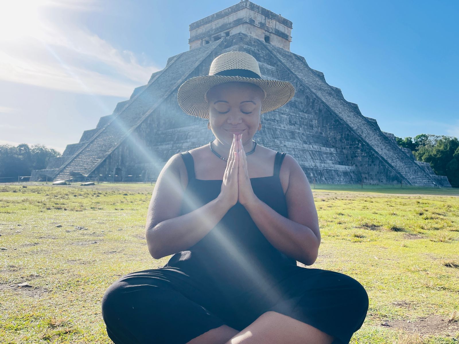 Woods sitting crossed leg with prayer hands in front of pyramid at Chichen Itza