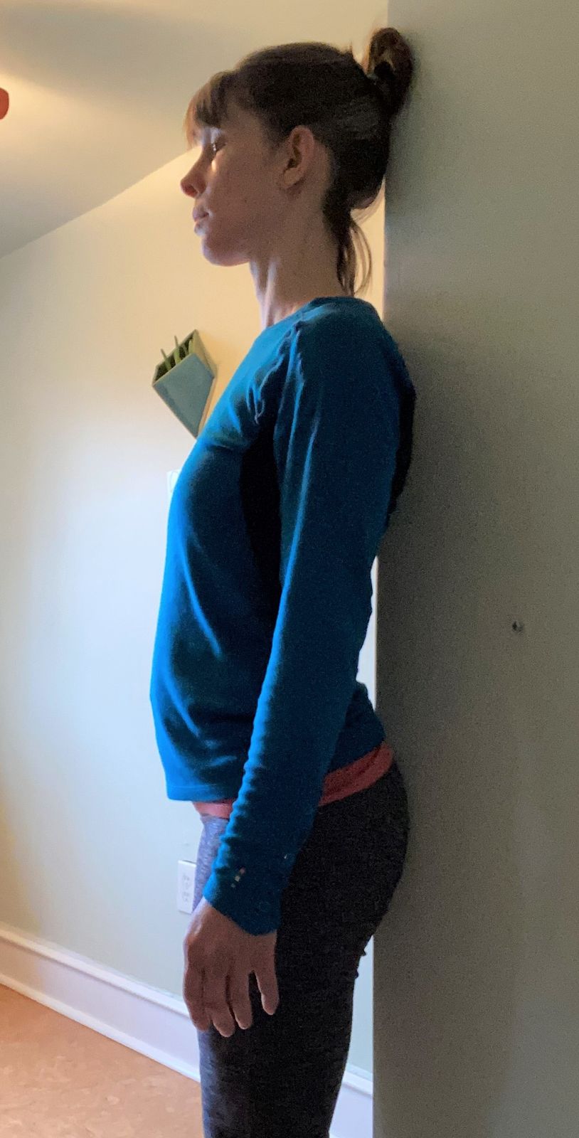 Here, my pelvis is tipping forward and my ribs are pushed forward too, so there's a lot of space between my low back and the wall.