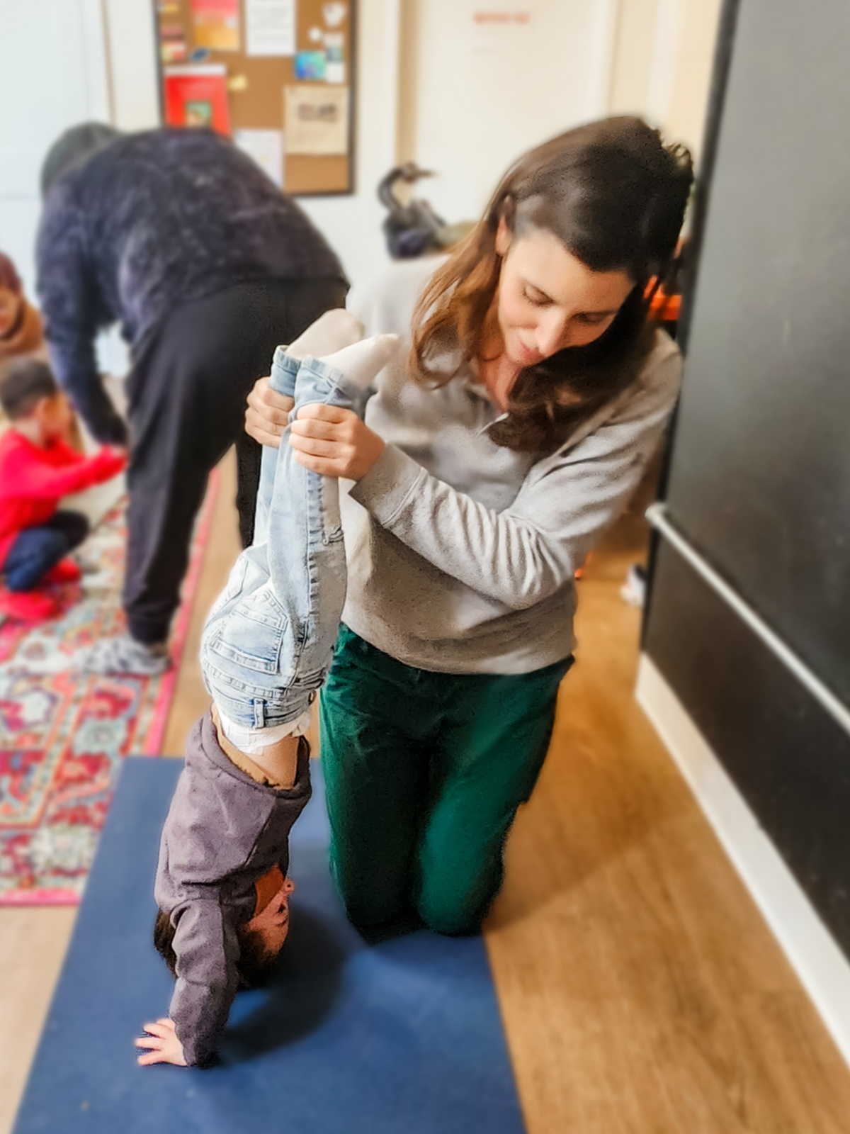 Corinne assisting John with his handstand at Toddler Yoga