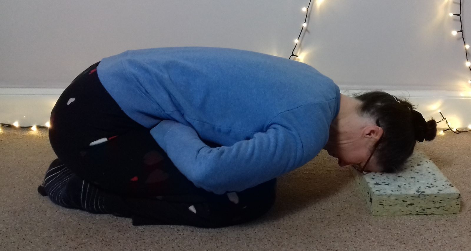 Image: Balasana with fists tucked into top of thighs/into groin 