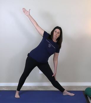 A woman in her 50s confidently practicing yoga online in the safety of her home.