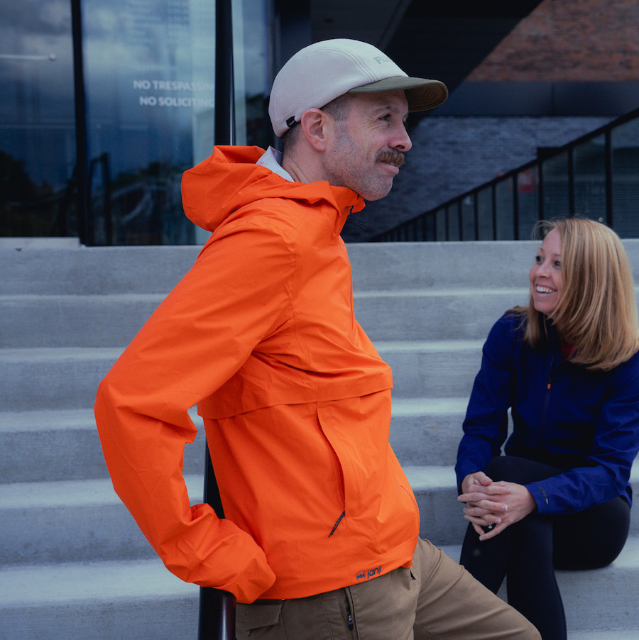 man wearing an orange rain jacket standing