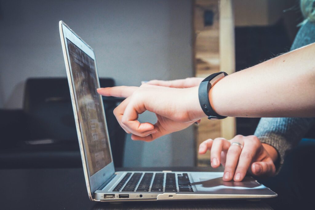 Dos personas señalando la pantalla de un computador, representando a dos personas buscando información sobre optimización para motores de búsqueda. 