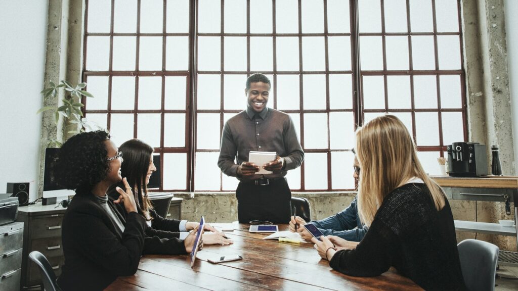 Cuatro compañeros de trabajo en una oficina, representando a varias personas hablando sobre los beneficios del marketing digital. 