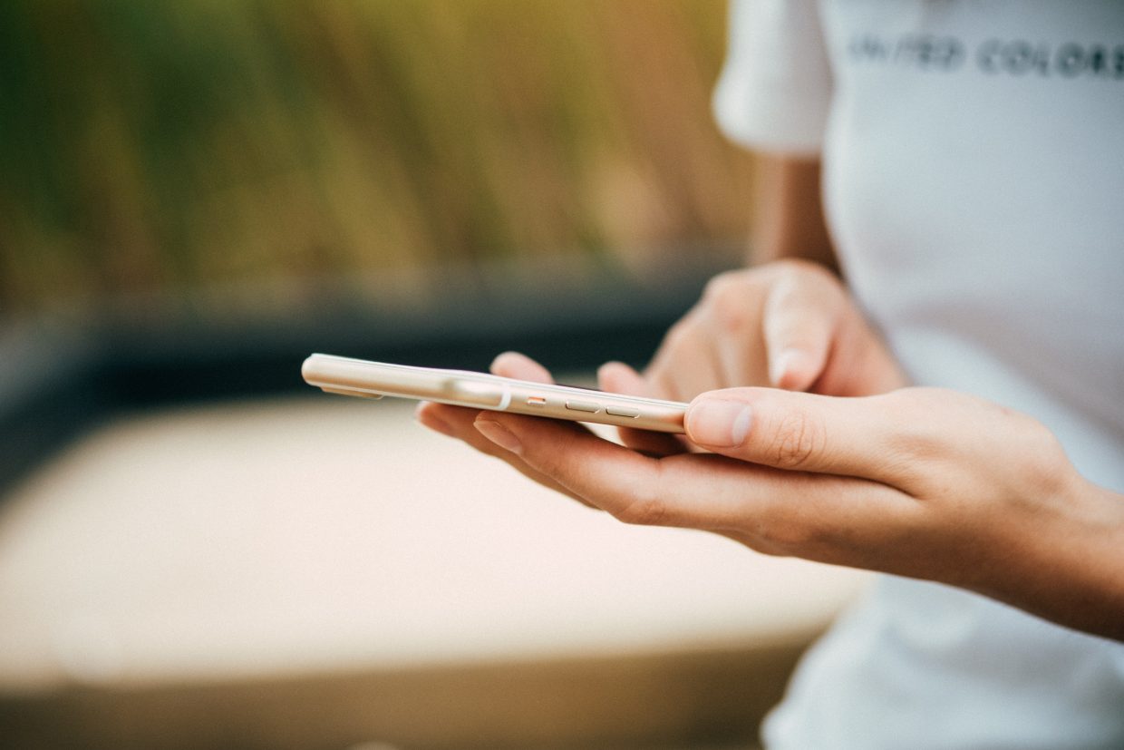 Image of woman scrolling on iPhone outside