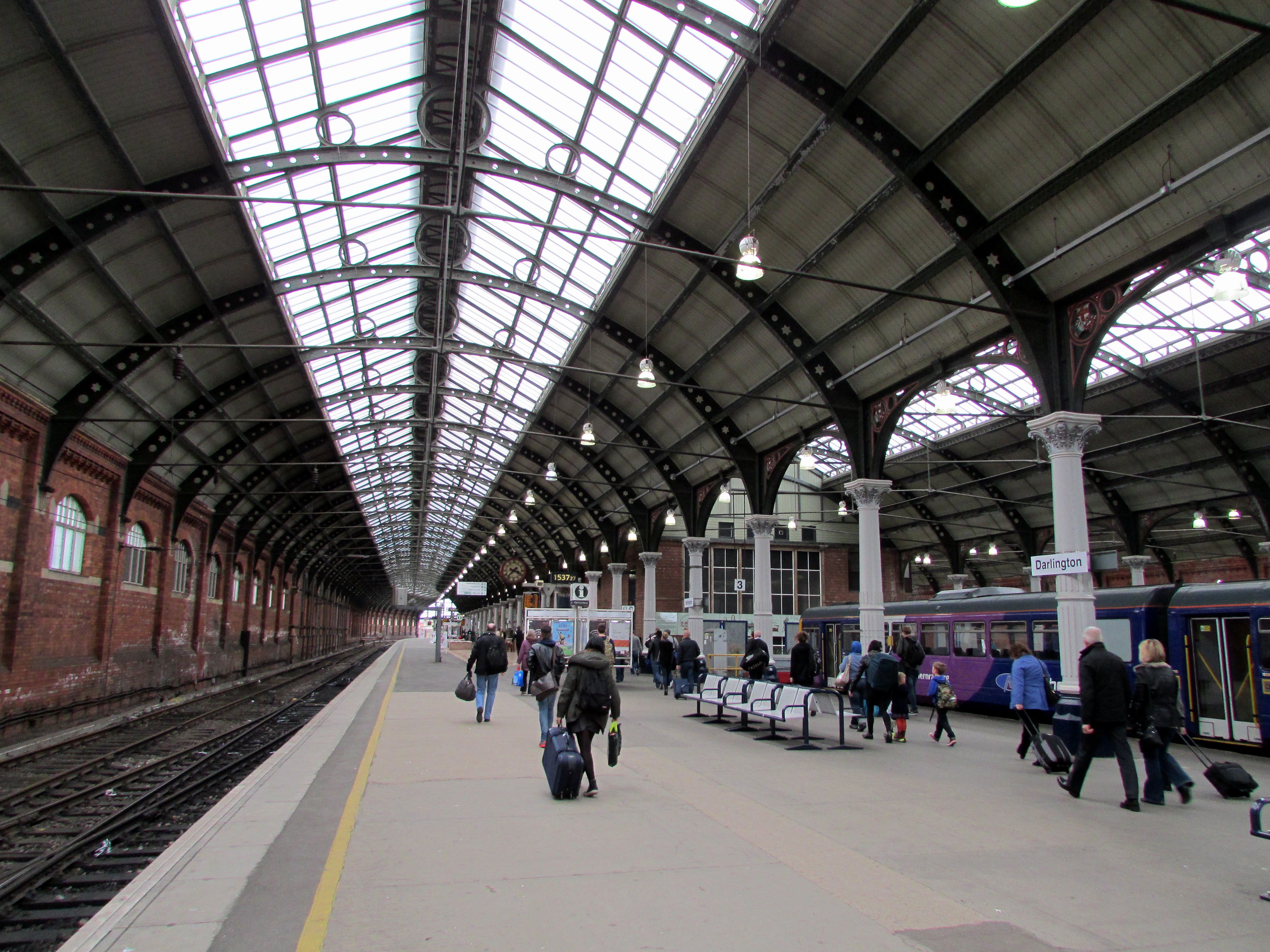 A railway station with some passengers walking alongside a rail track