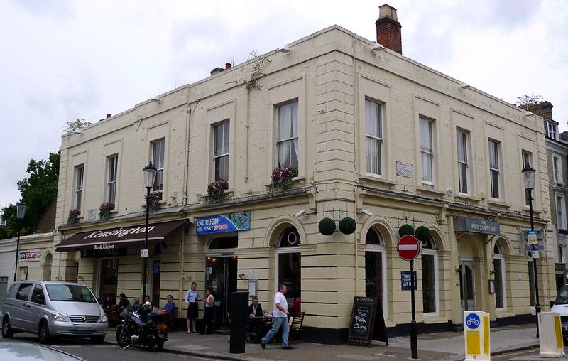 People and vehicles in front of a corner pub.jpg