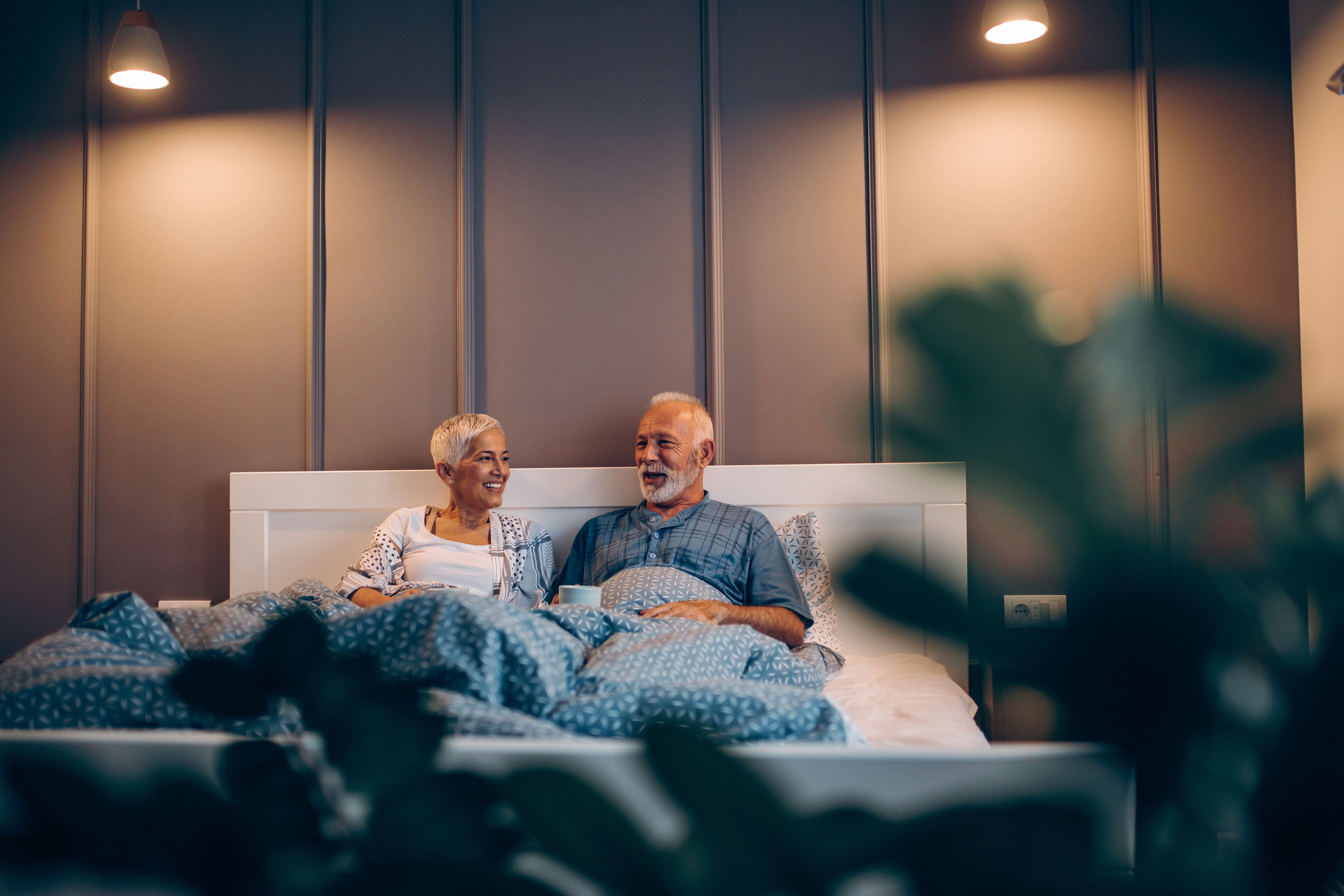 A senior couple chatting on their bed and enjoying their modern furnished Build To Rent apartment.