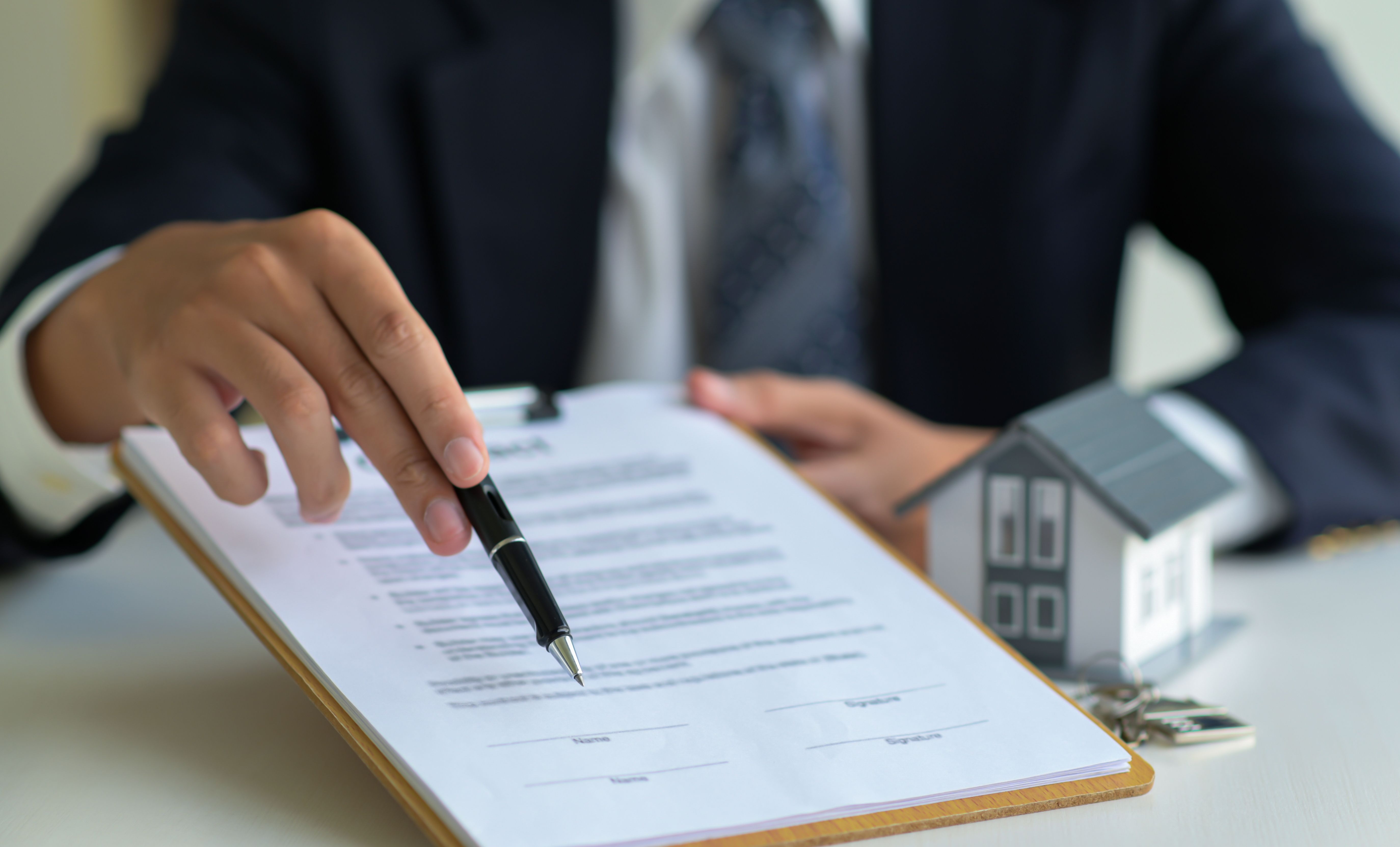 close up shot of house broker pointing the pen on the paper