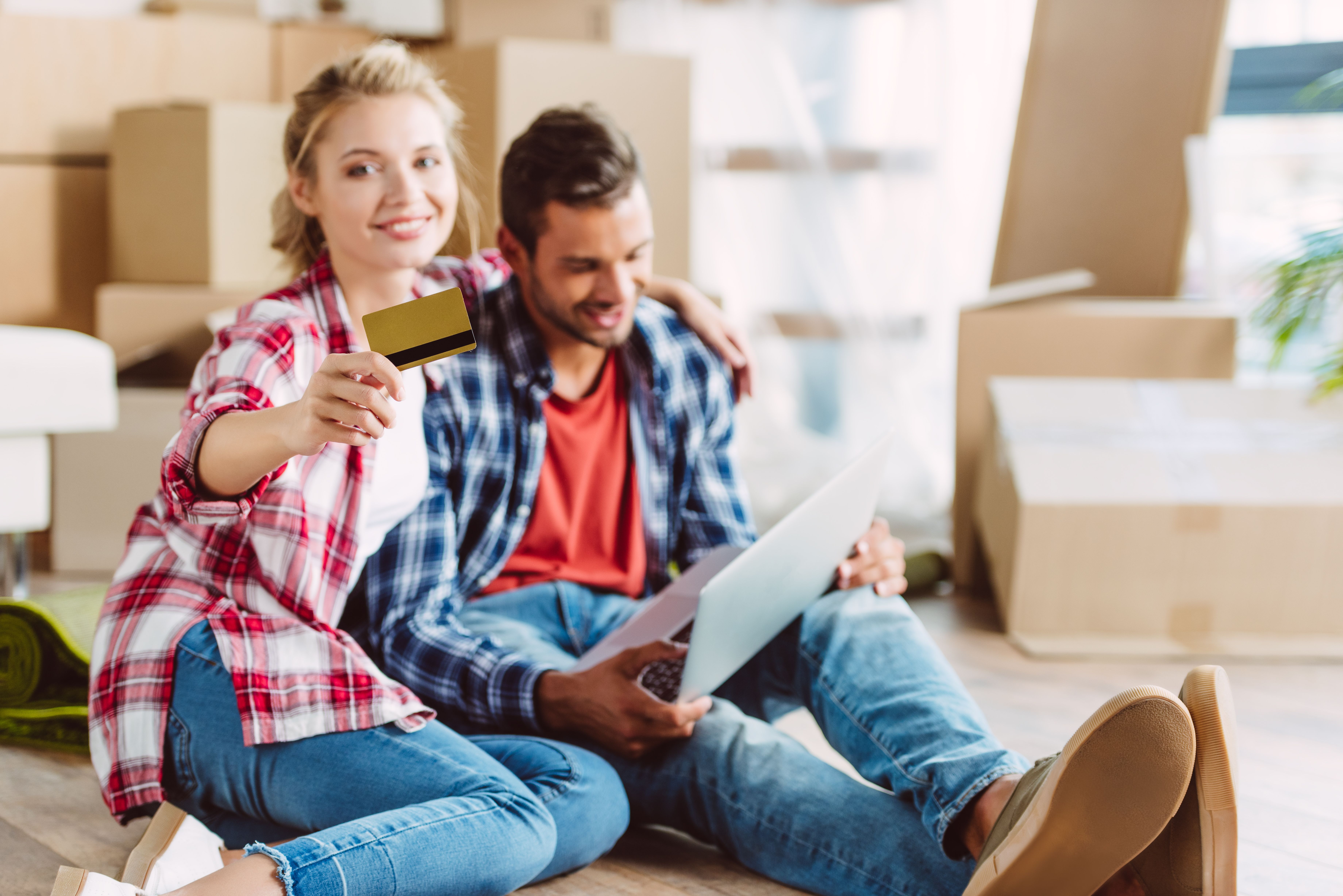 A Build To Rent resident couple holding a credit card while checking the costs of moving house.