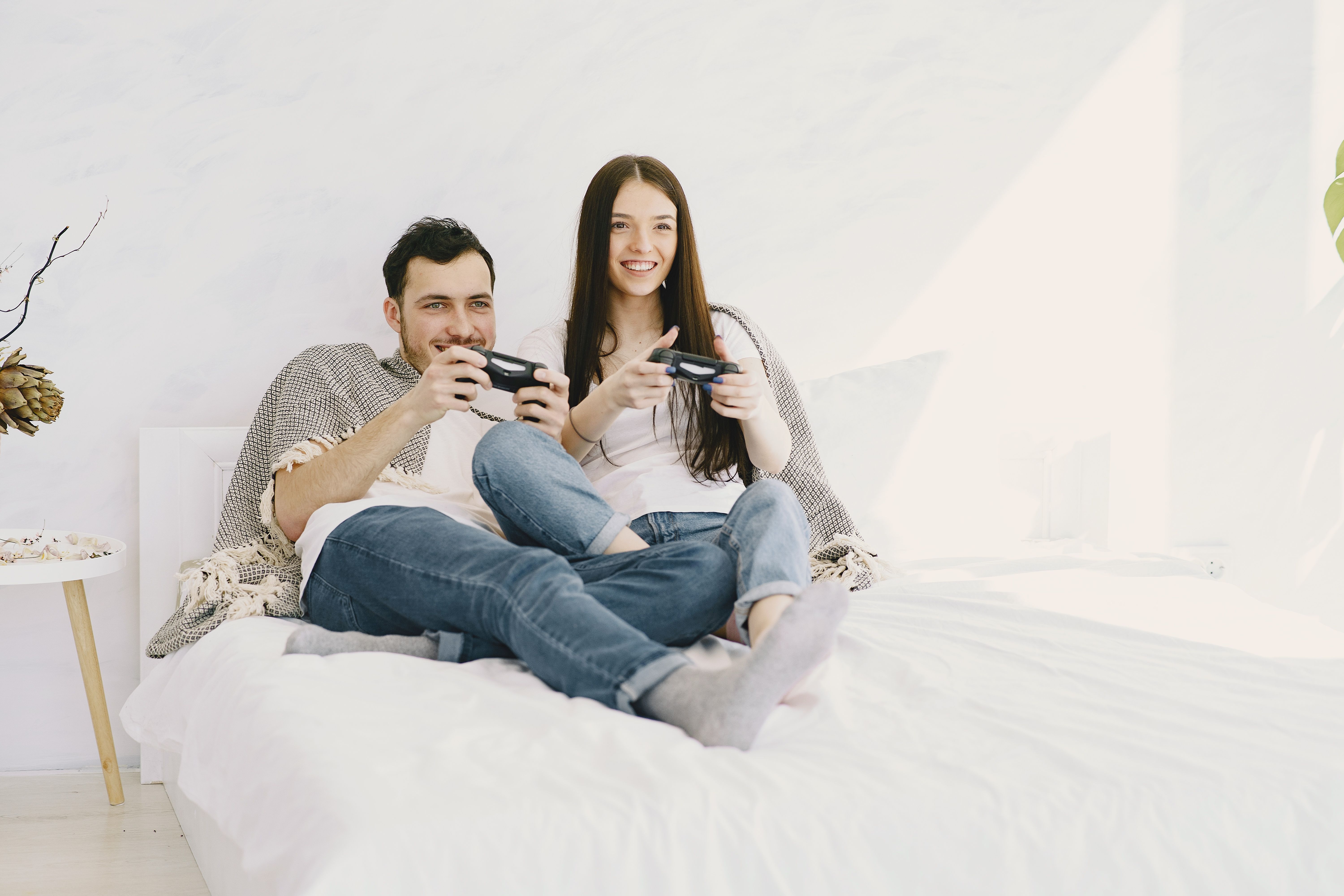 A happy couple playing video games on their bed in a Build To Rent property during their COVID-19 quarantine.