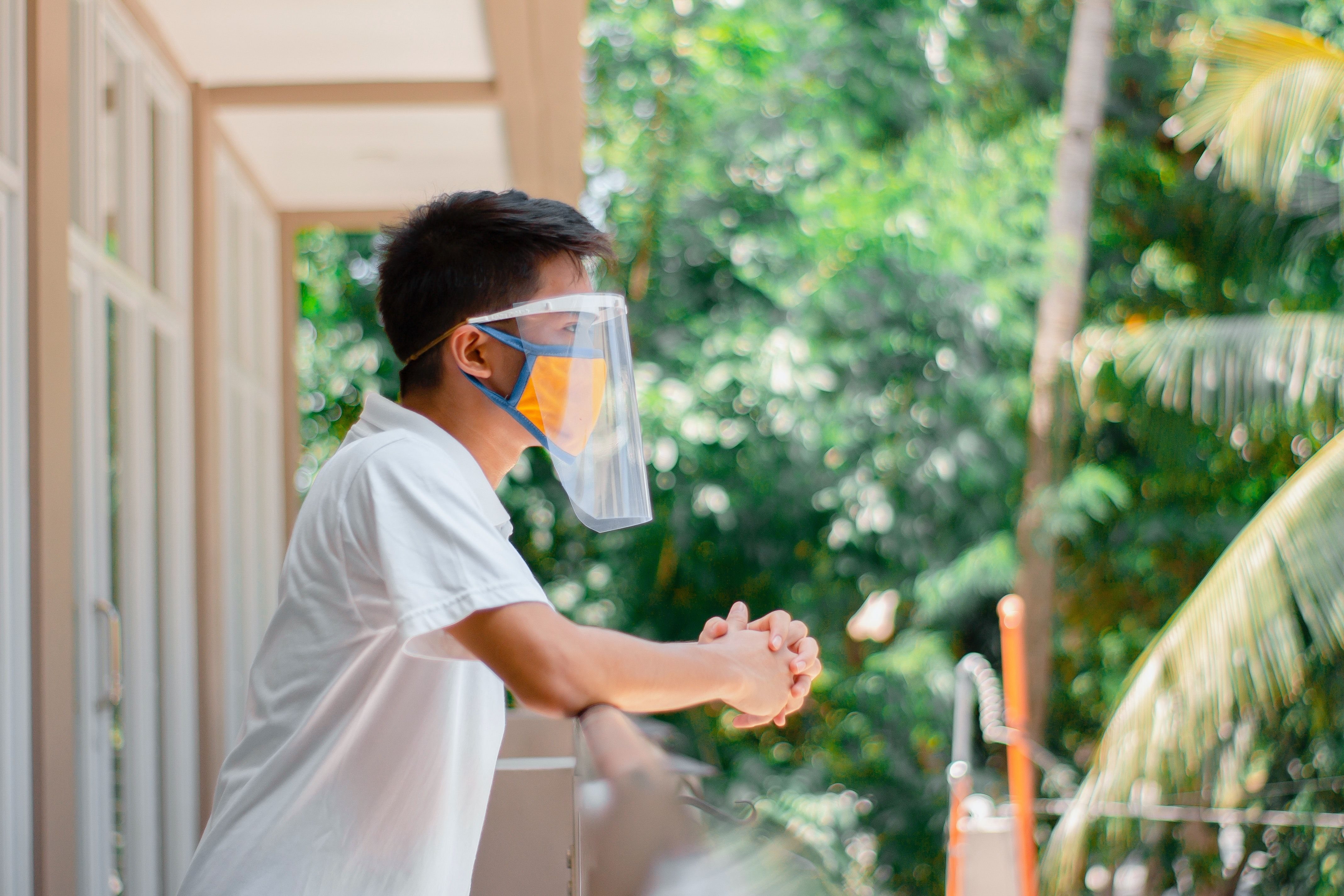 A male tenant at a Build To Rent development wearing a mask and standing alone on the balcony to protect himself from Coronavirus.