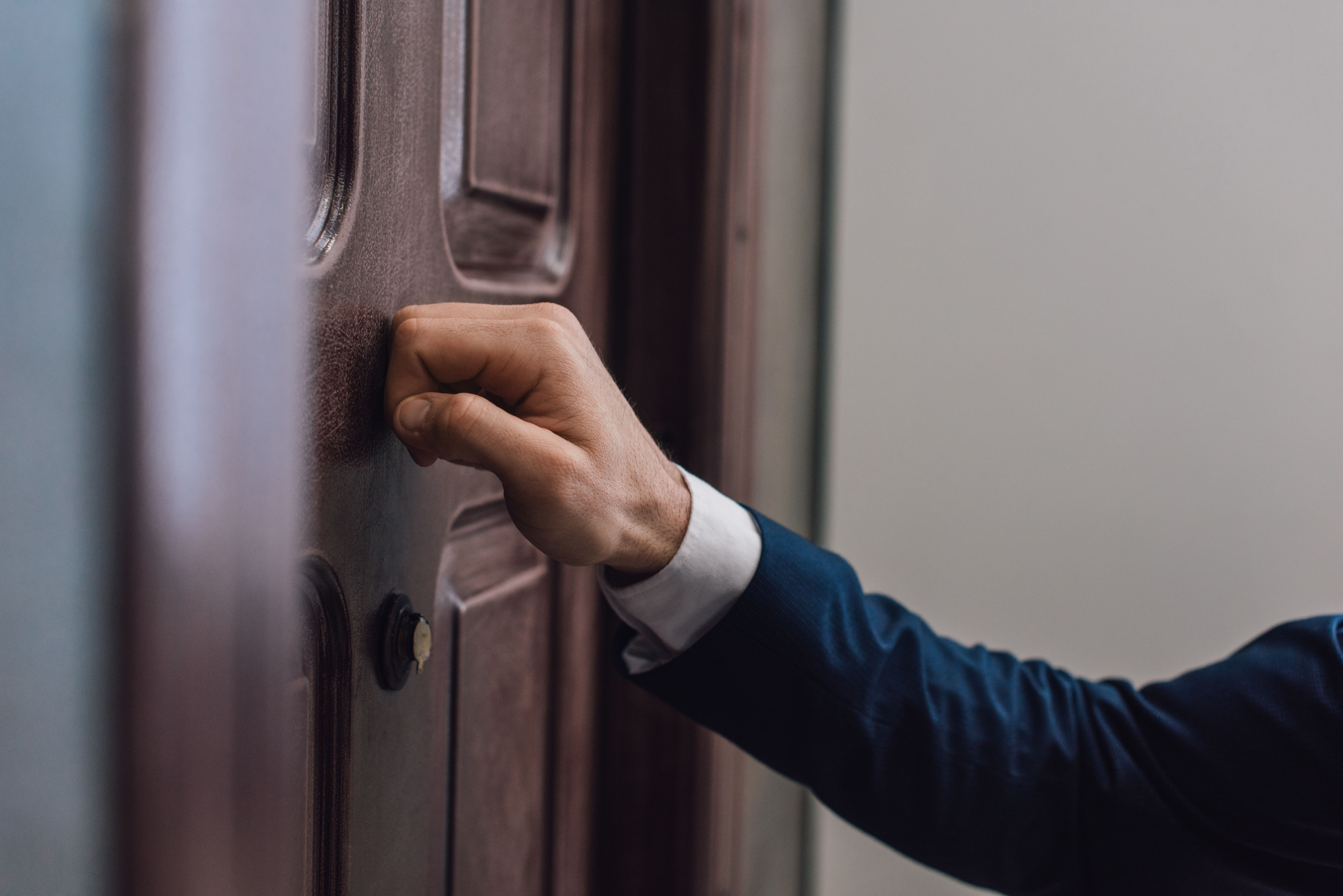 A men knocking on a door with his hand