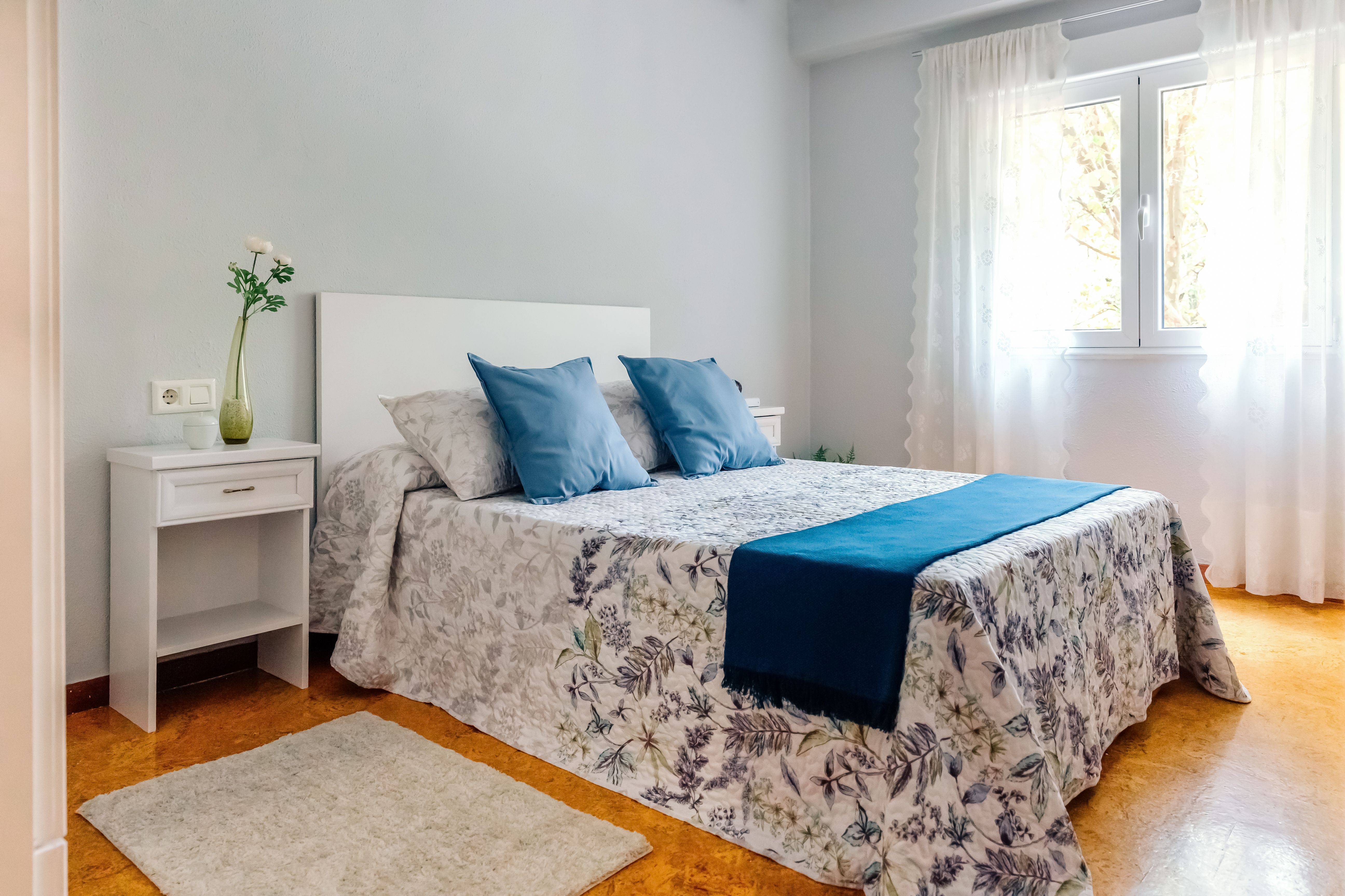 Interior of a cosy bedroom decorated with quilt and curtains