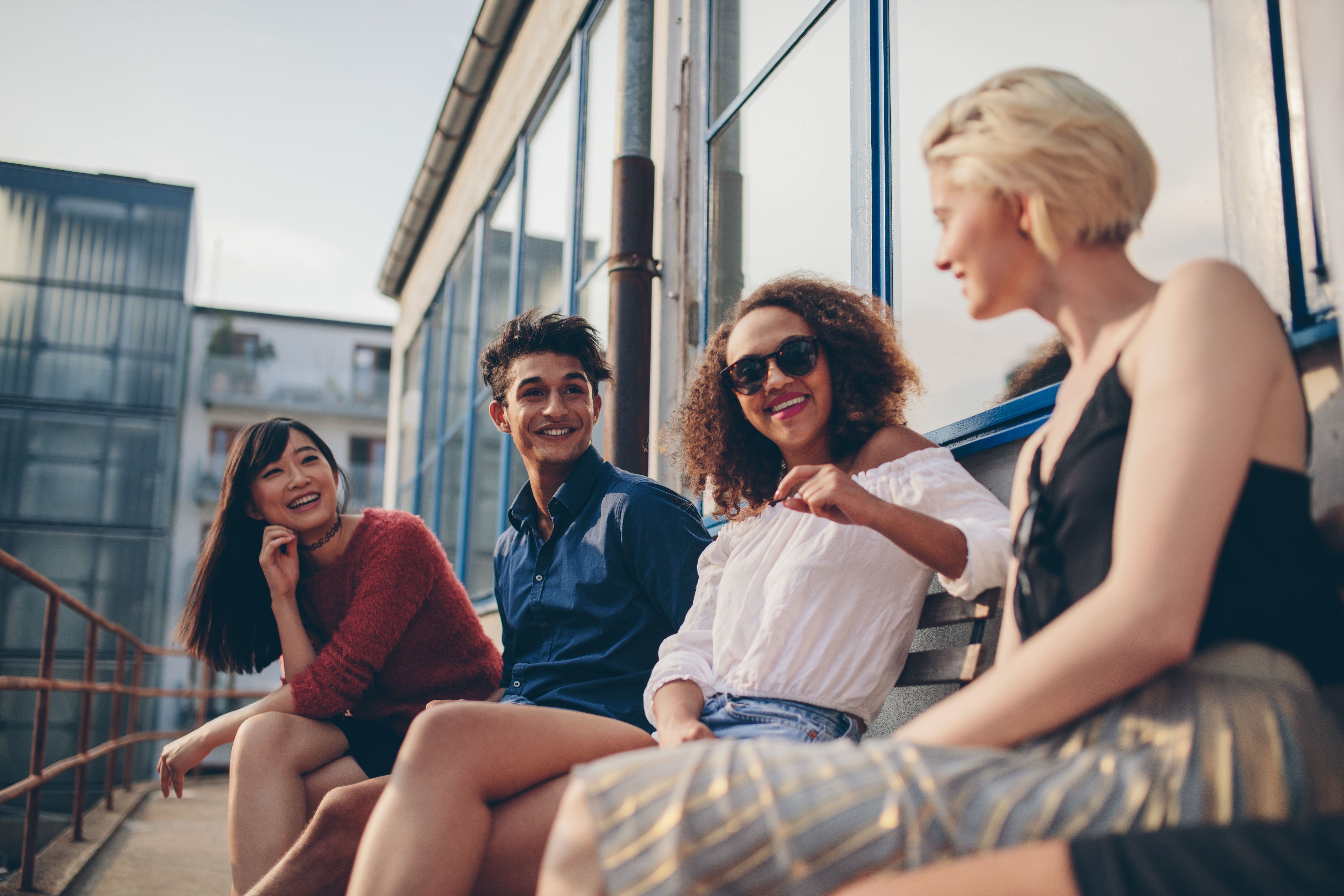 A group of friends gather and socialise in a sunny, south-facing balcony at one member's Build To Rent apartment.